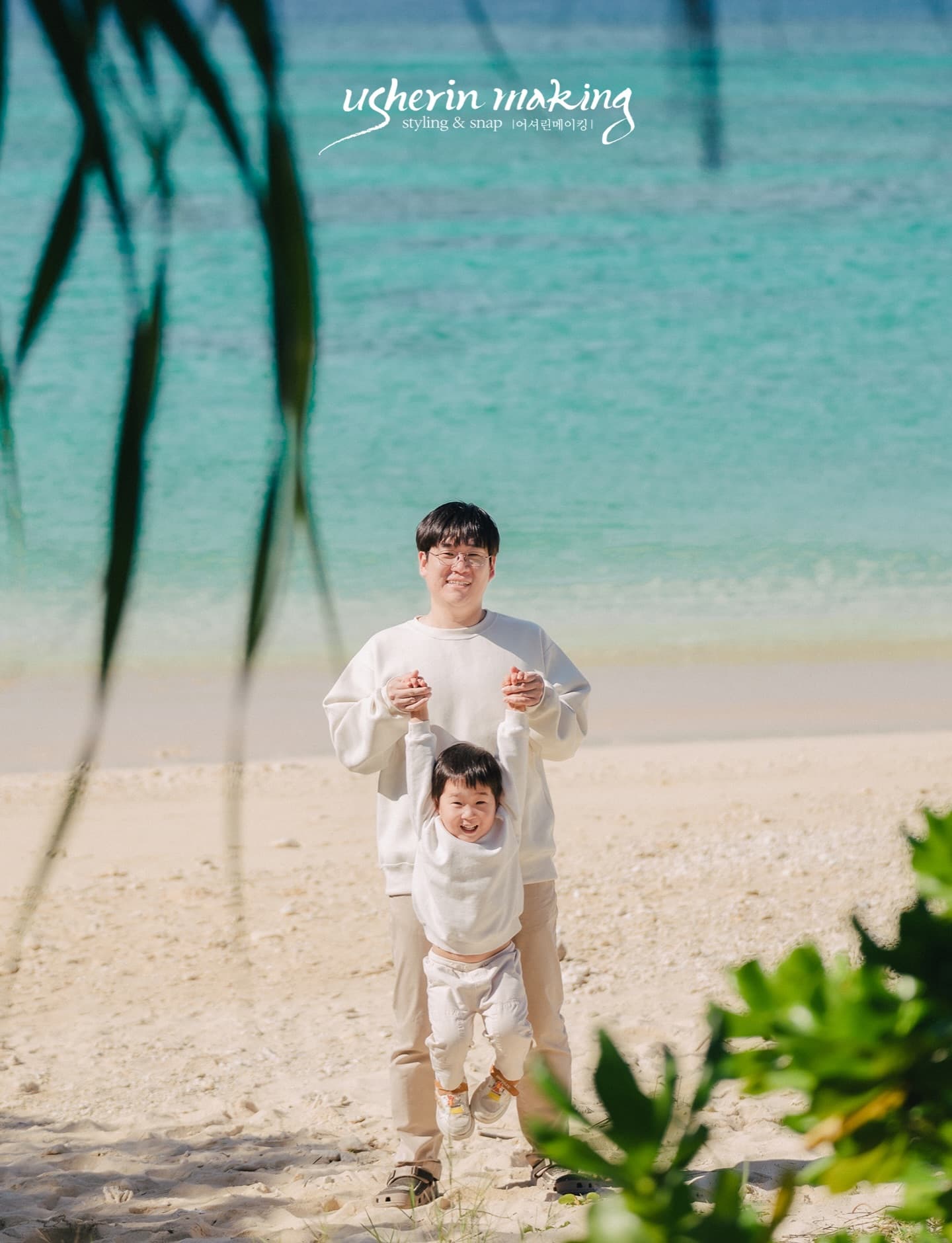Father playing with his toddler in front of the emerald sea in Okinawa