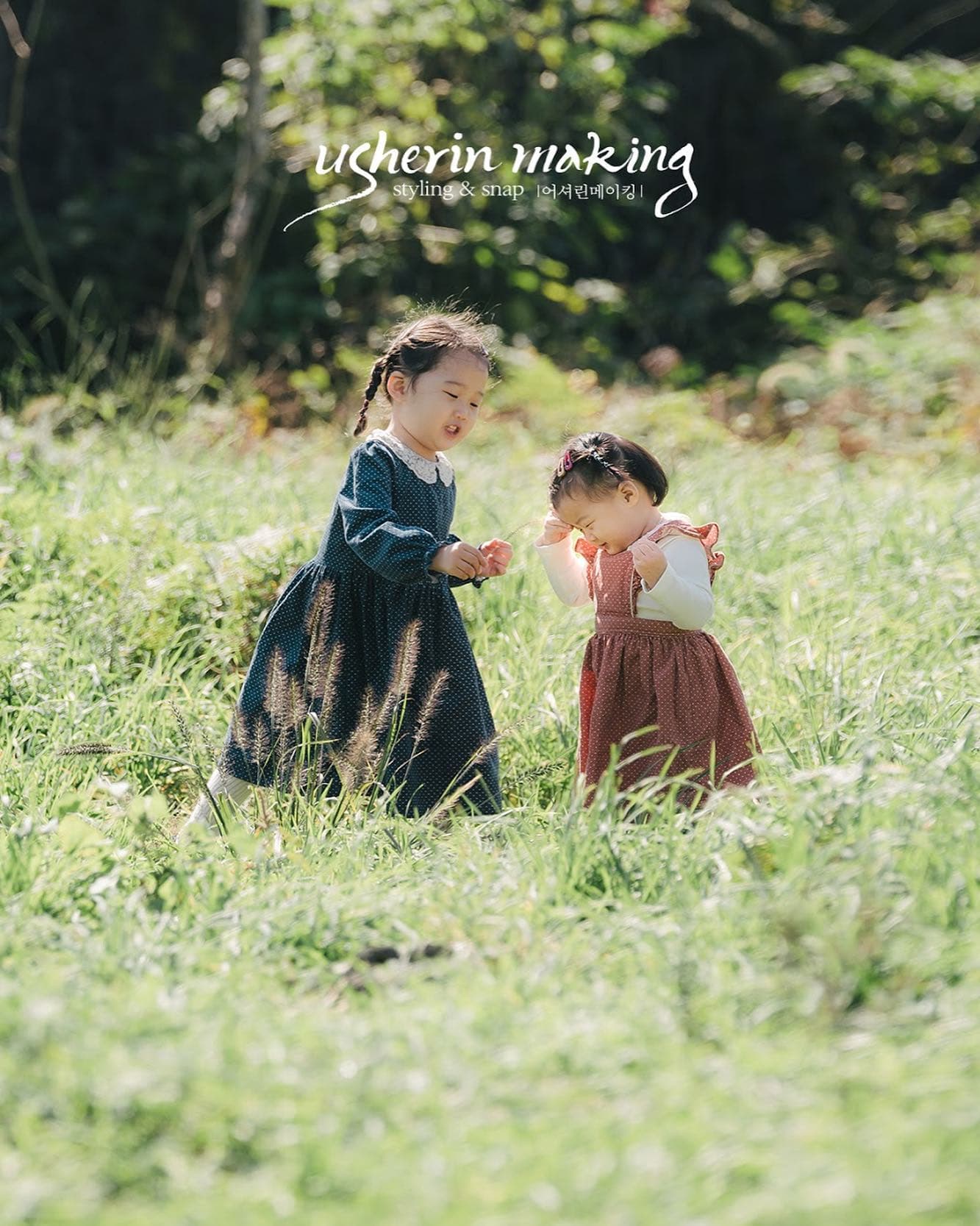 陽だまりの草原で遊ぶ、ワンピース姿の幼い姉妹