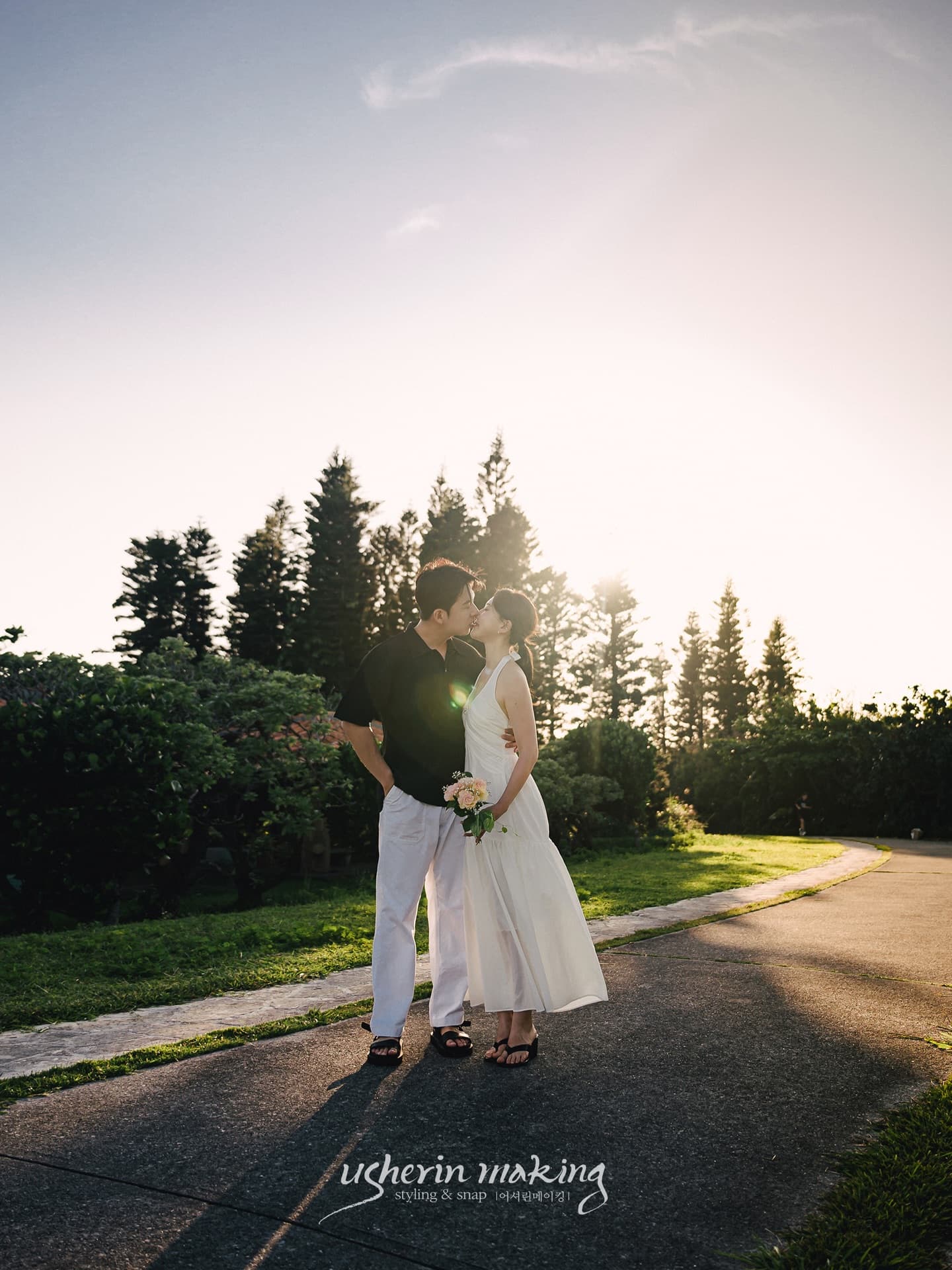 Backlit couple sharing a kiss on a garden path at sunset in Okinawa