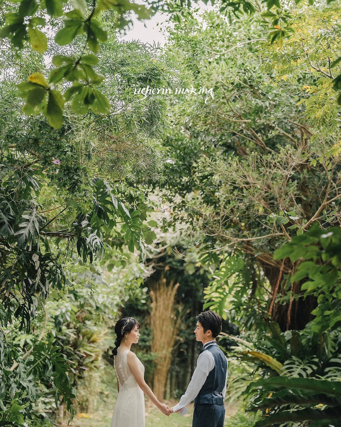 Bride and groom holding hands on a path through lush subtropical greenery in Okinawa