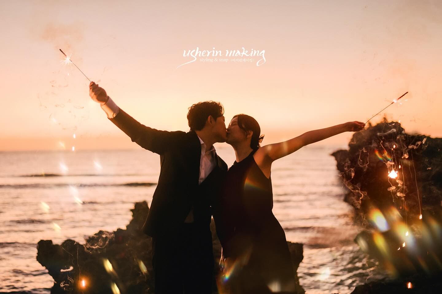Couple kissing with lit sparklers by the sea at sunset, Okinawa