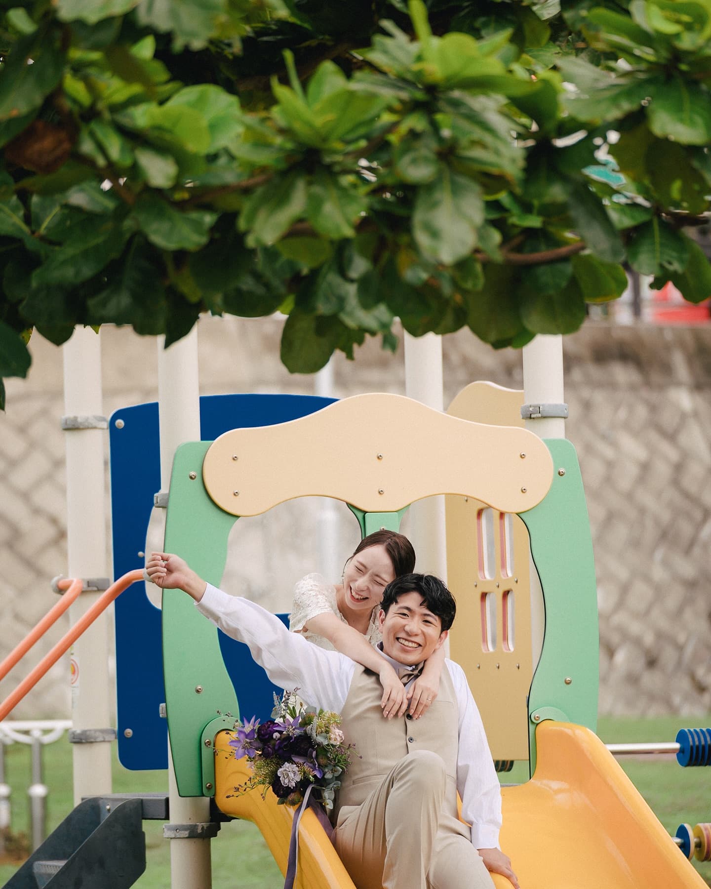 Bride hugging the groom from behind on a playground slide in Okinawa