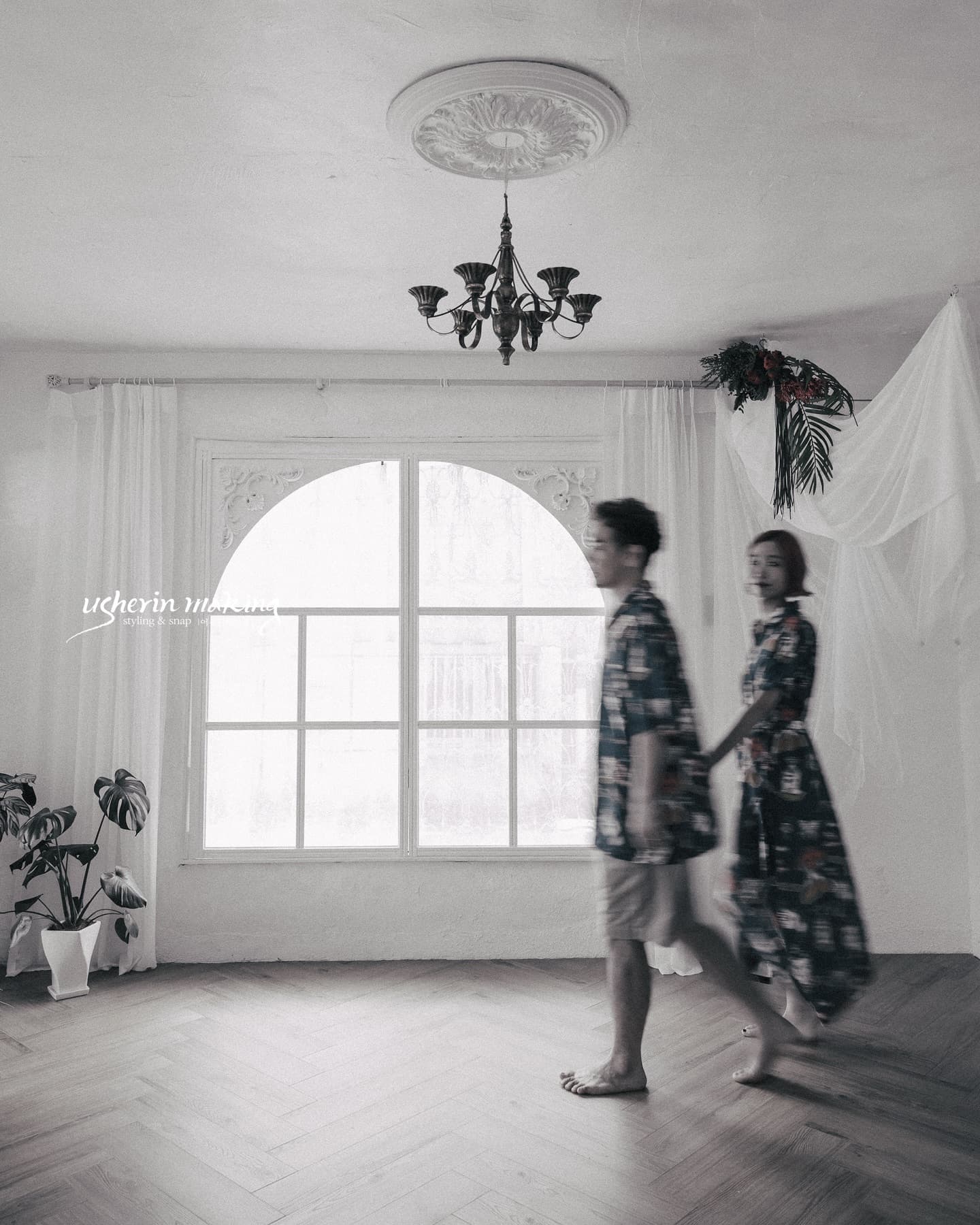 Couple in matching prints strolling through an arched-window studio