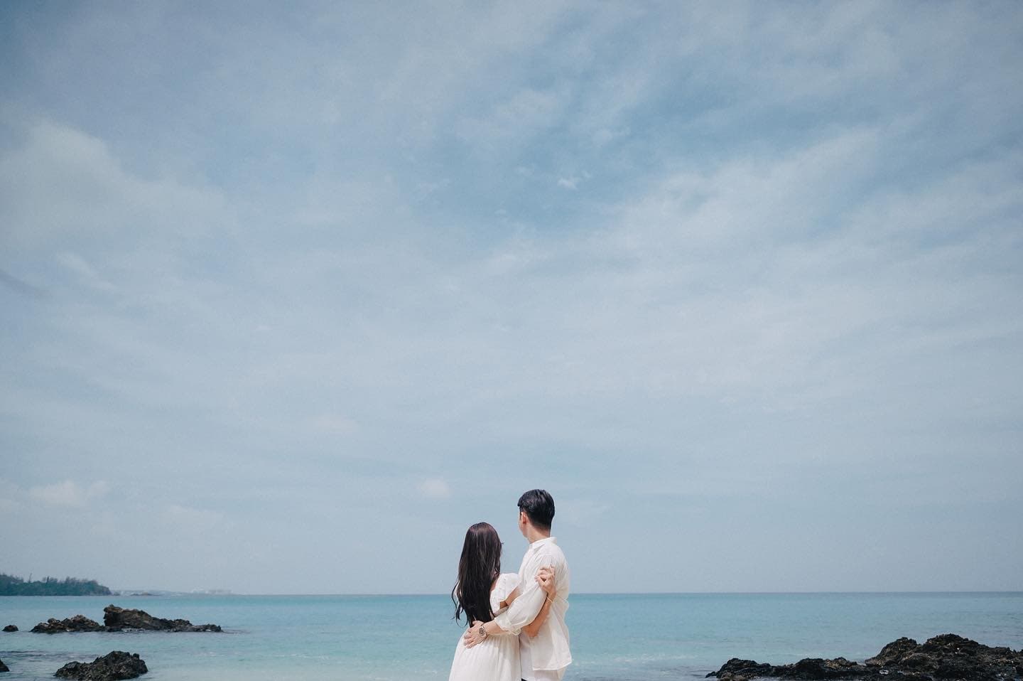Back view of a couple gazing at the emerald sea, Okinawa